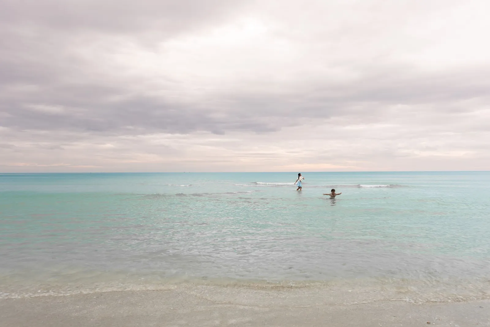 Children playing at the beach in Trat, Thailand under a cloudy sky